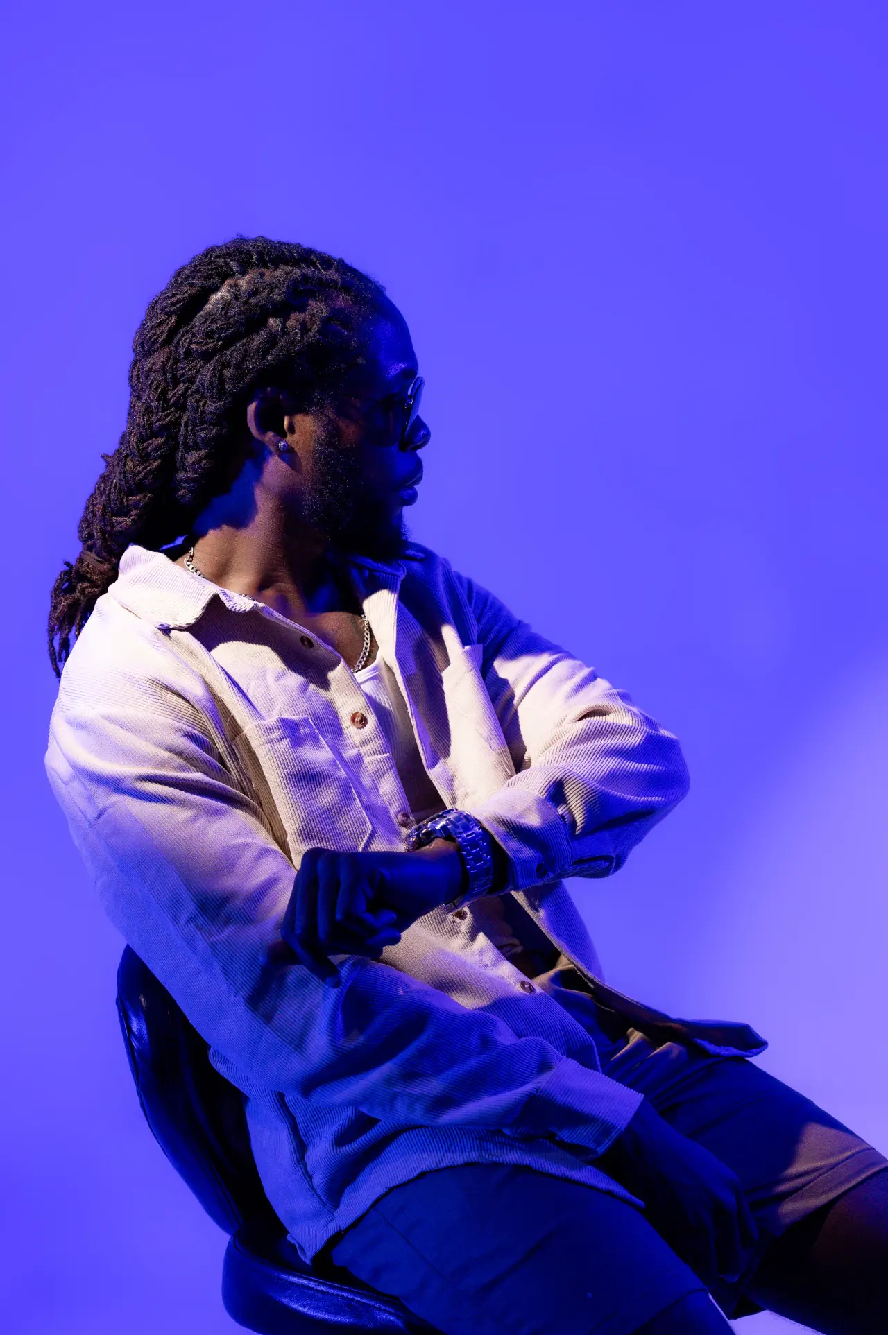 Saint Chris pointing upward in a blue studio portrait.