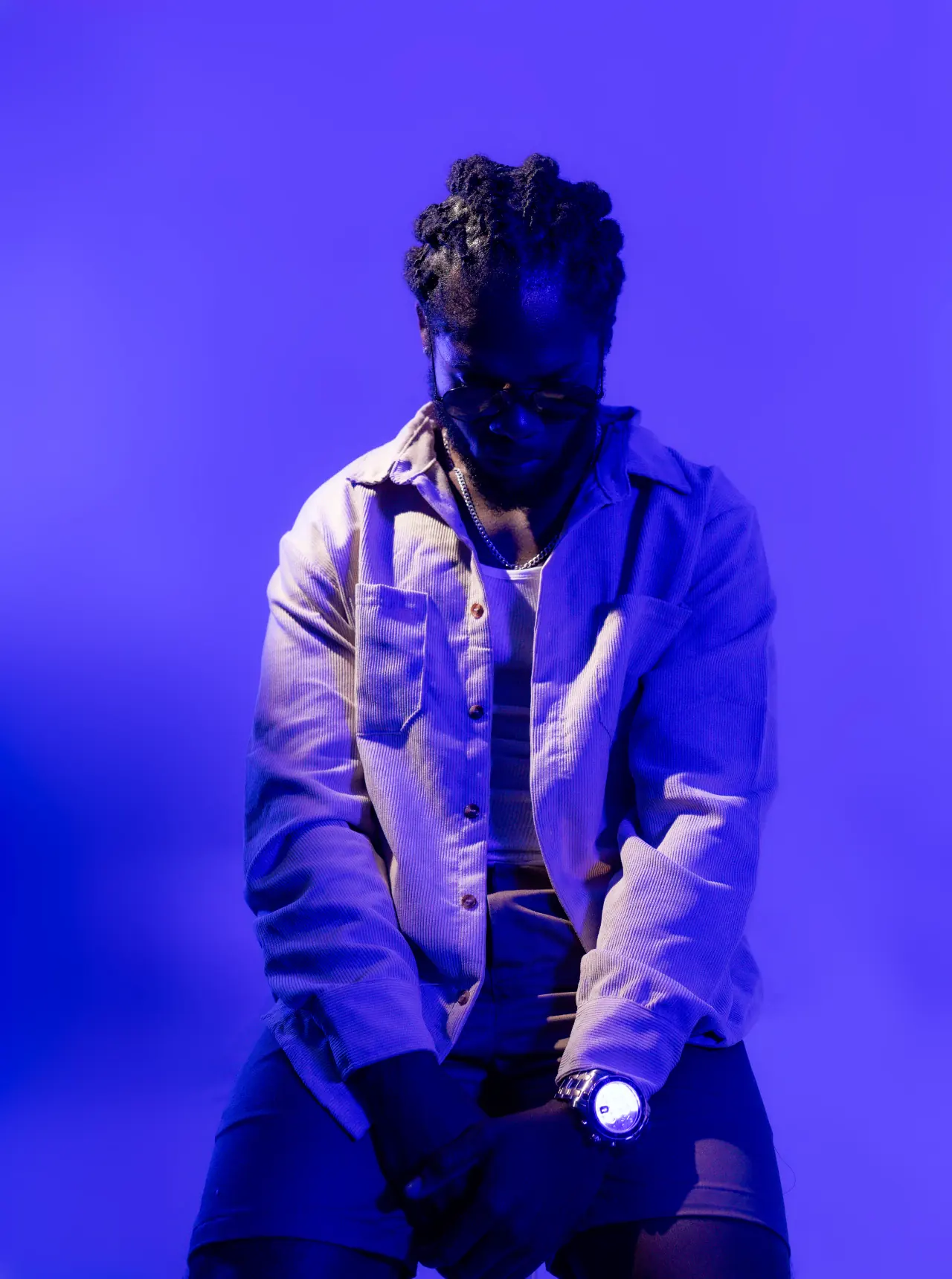 Saint Chris seated profile portrait in violet-blue light.